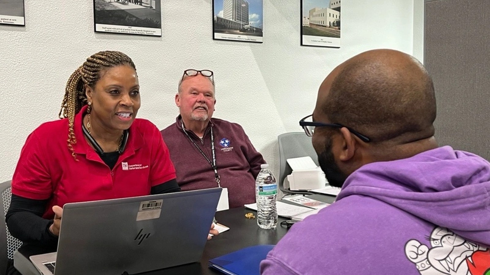 Veterans-service staff speak with a veteran across a table during an in-person claims-assistance clinic.