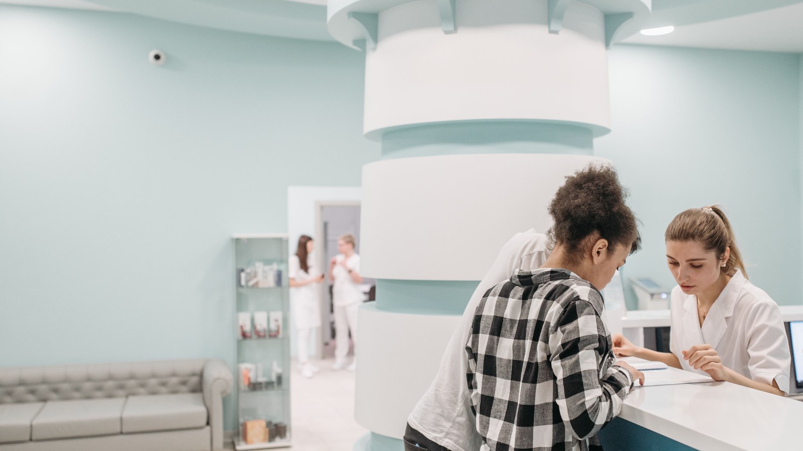 People at a clinic reception desk looking at documents.