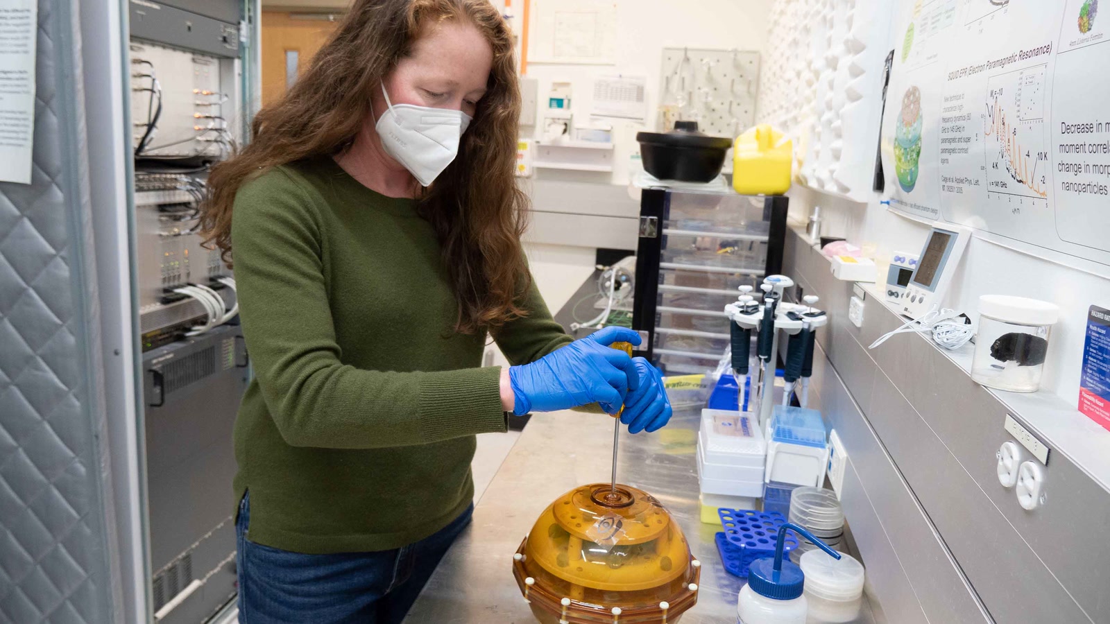 NIST engineer Katy Keenan works with a round amber MRI calibration phantom at a laboratory bench.